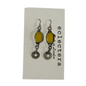 A pair of handmade dangle earrings with oval yellow resin centers and silver-toned metal charms, displayed on a white backing card printed with the brand name 'eclectera'.