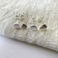 Silver heart-shaped earrings on a textured fabric surface