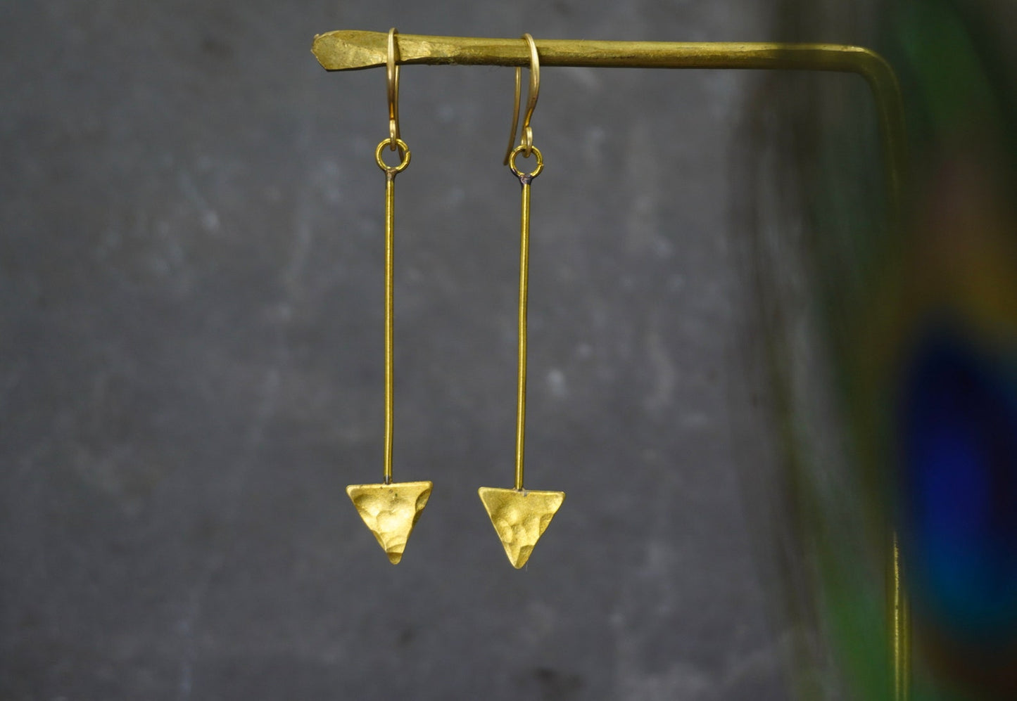 Gold triangle earrings on a dark gray background