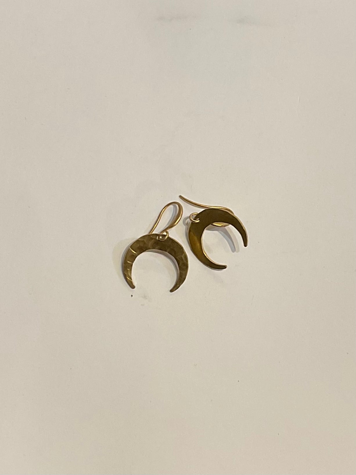 Pair of gold crescent moon earrings on a light gray background