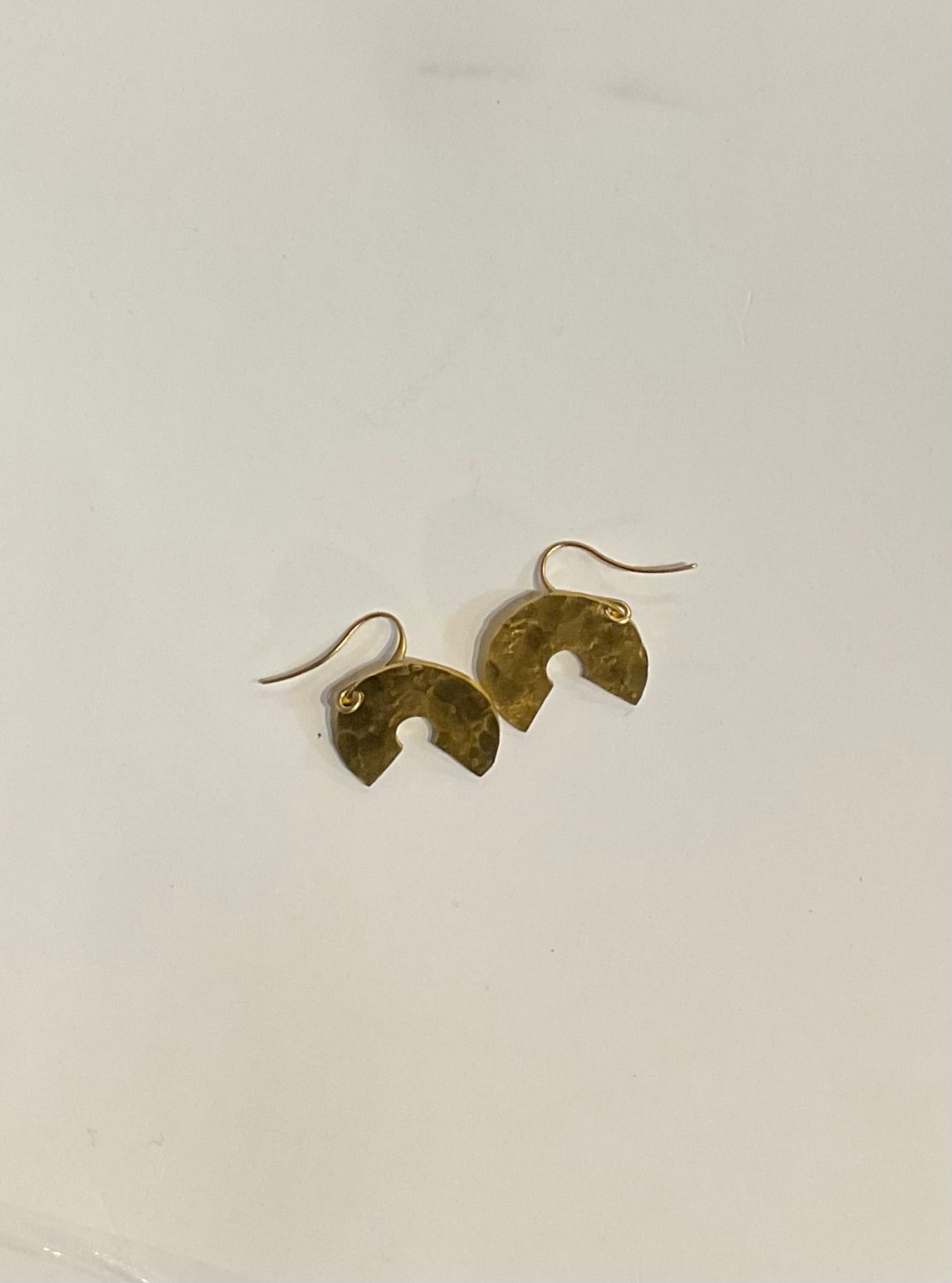 Gold earrings on a light gray background