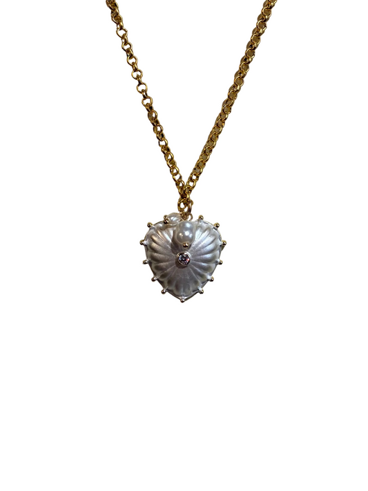 Gold chain necklace with a decorative pendant on a textured beige surface