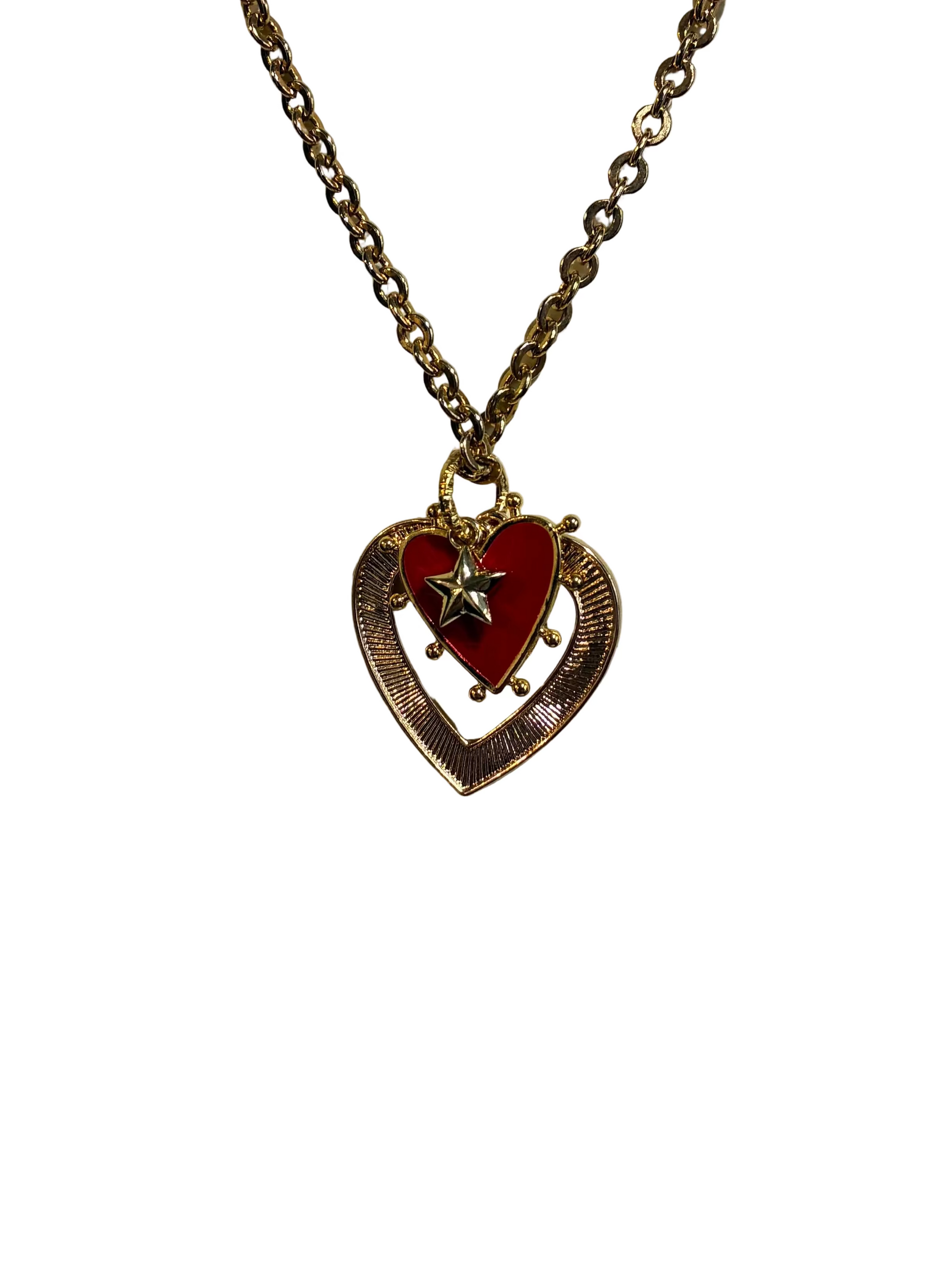 Heart-shaped pendant necklace with red center and gold chain on a textured beige background