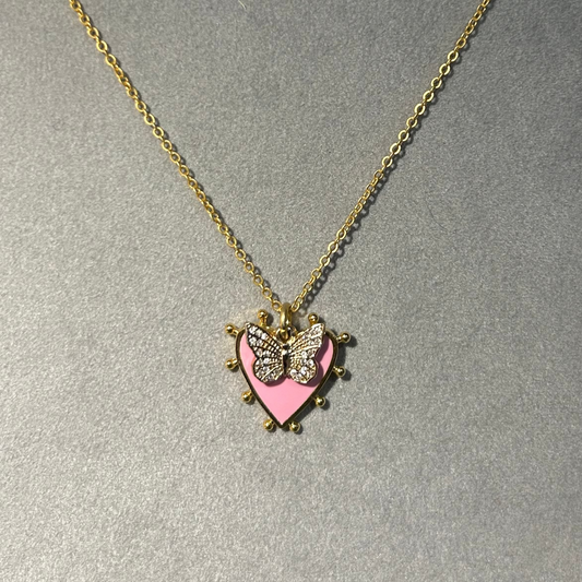 Necklace with a heart-shaped pendant featuring a butterfly design on a gray background, branded 'Pom Di Pom'.