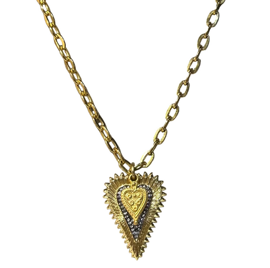 Gold chain necklace with a heart-shaped pendant on a gray background, branded 'Pom Di Pom'.