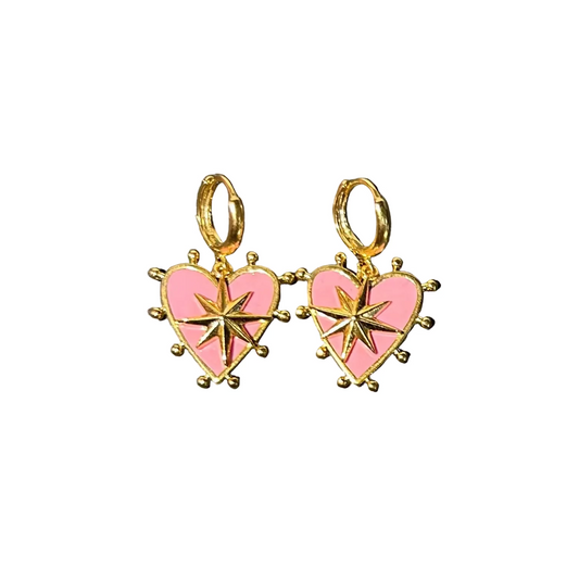 Heart-shaped earrings with pink centers and gold accents on a dark stone surface