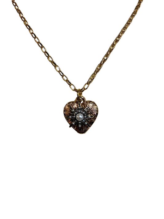 Heart-shaped pendant necklace with a pearl on a beige stone surface