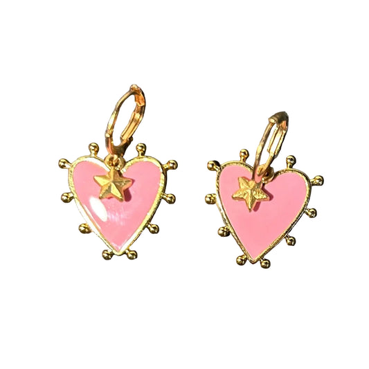 Heart-shaped earrings with pink centers and gold accents on a dark surface