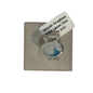 A silver-toned ring with a round bezel containing milky white seaglass with a blue inlay, mounted on a textured beige display card with a white tag reading 'Seaglass from Japan 