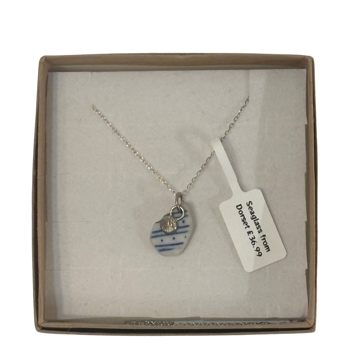 A frosted piece of glass collected from Dorset, paired with a sterling silver shell hung on a sterling silver 18 inch belcher chain.