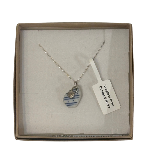 A frosted piece of glass collected from Dorset, paired with a sterling silver shell hung on a sterling silver 18 inch belcher chain.
