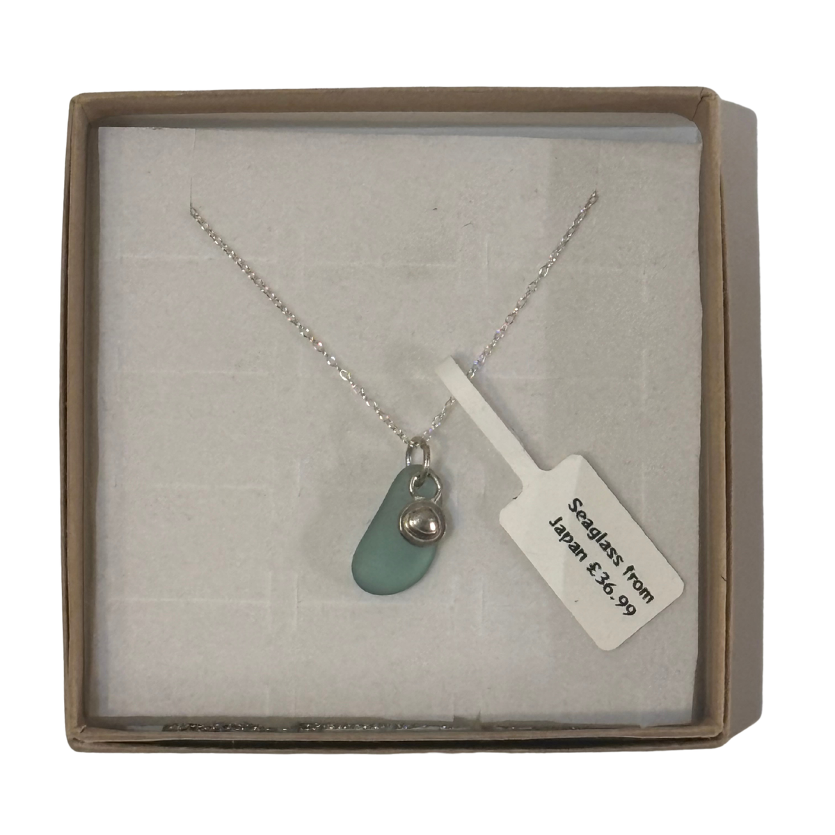 A frosted piece of green glass with collected from Japan, paired with a sterling silver shell hung on a sterling silver 18 inch belcher chain.