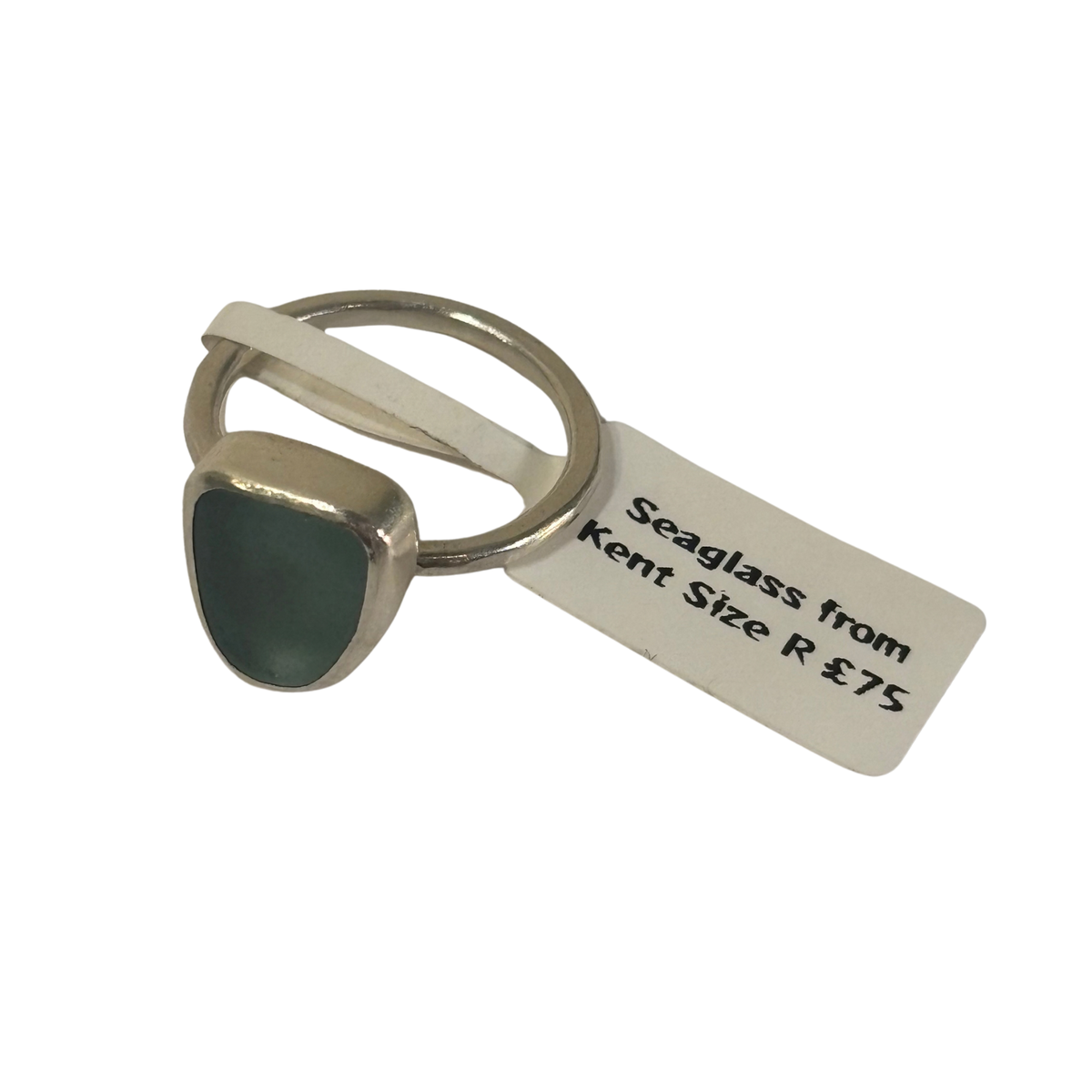A silver-toned ring with a triangular dark green seaglass stone, shown with a white paper tag that reads 'Seaglass from Kent Size R £75'.