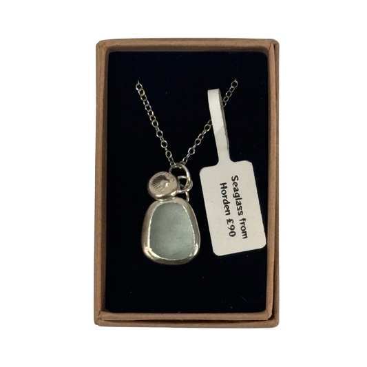 A silver necklace with a sea glass pendant and a small aqua stone, presented in a brown gift box with a black insert and a white tag that reads 'Sea glass from Horden.