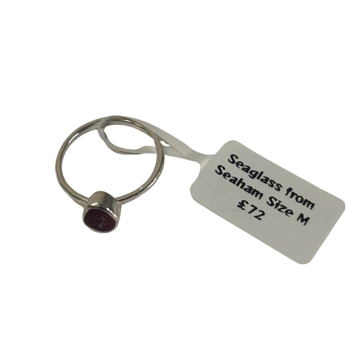 A silver-toned seaglass ring with a small oval dark red seaglass stone, shown with a white paper tag that reads 'Seaglass from Seaham Size M £72' on a plain white background.