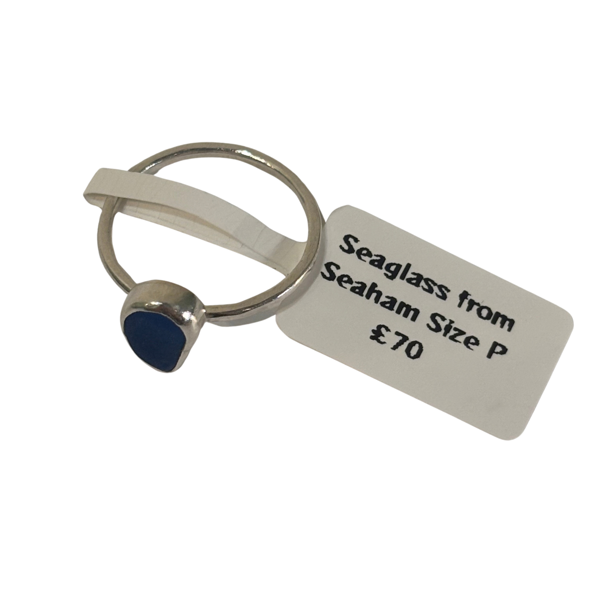 A silver-toned ring with a small oval blue seaglass stone, attached to a white paper tag that reads 'Seaglass from Seaham Size P £70' on a plain white background.