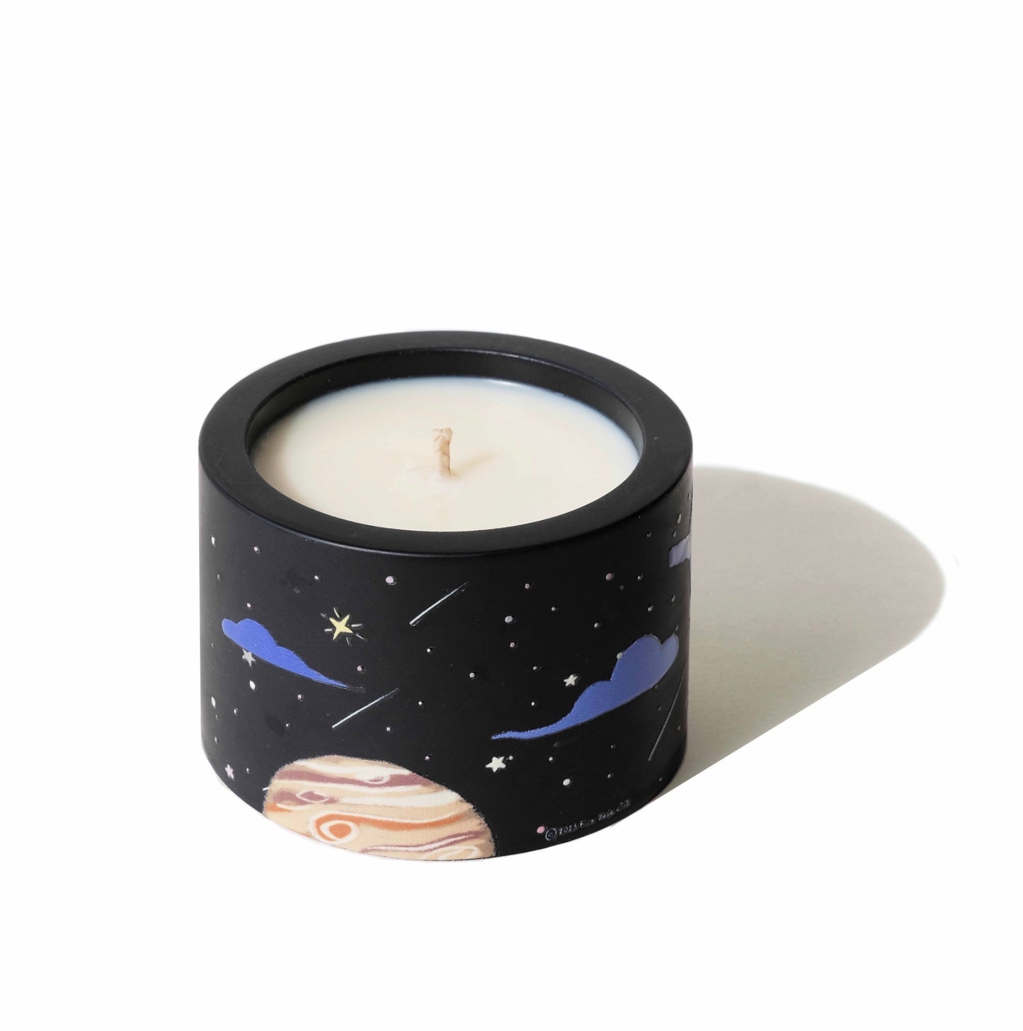 Candle in a container with space-themed design on a white background