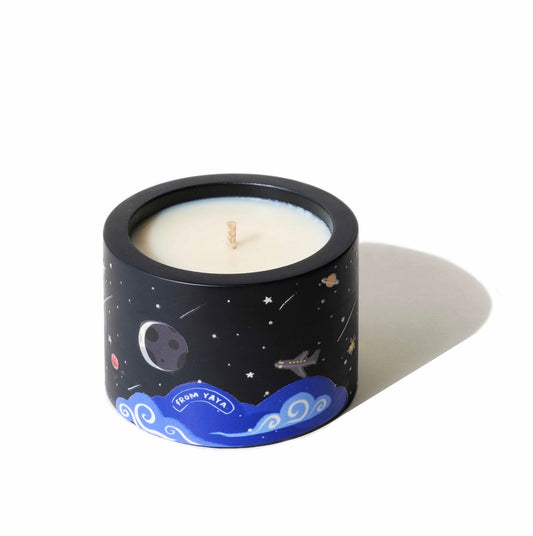 Candle in a black container with space-themed design on a white background